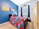 A cozy bedroom featuring a patchwork quilt, dark wood furniture, and a blue accent wall at 13304 Mandalay Pl, Spring Hill, FL 34609
