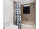 Clean bathroom featuring a combined tub and shower, neutral tiling, updated fixtures and a patterned shower curtain at 1382 Aladdin Rd, Spring Hill, FL 34609