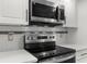 Stainless steel microwave and glass top range with white cabinets and subway tile backsplash at 1382 Aladdin Rd, Spring Hill, FL 34609