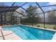 Beautiful screened-in pool with clear blue water, surrounded by landscaping and an open sky view at 1382 Aladdin Rd, Spring Hill, FL 34609