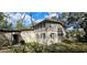 Tan two-story home showcasing a well-lit exterior with a light-colored foundation, shutters, and lots of tree coverage at 17932 Wendy Sue Ave, Hudson, FL 34667