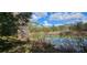 The property pond reflecting a clear sky with scattered clouds, surrounded by natural vegetation at 17932 Wendy Sue Ave, Hudson, FL 34667