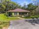 Inviting single-story home featuring a metal roof, covered porch, and beautifully landscaped yard, perfect for outdoor enjoyment at 22000 Snow Hill Rd, Brooksville, FL 34601