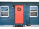 Close-up of a coral front door adorned with a wreath, flanked by symmetrical windows at 291 115Th Ave, Treasure Island, FL 33706