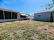 View of the backyard with a detached garage and screened in porch under a clear blue sky at 3243 Bayport Dr, Holiday, FL 34691