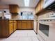 Bright kitchen featuring modern appliances, wood cabinetry, tile floors, and stone countertops at 3243 Bayport Dr, Holiday, FL 34691