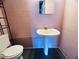 Functional powder room featuring a pedestal sink, toilet, and block wall at 3243 Bayport Dr, Holiday, FL 34691