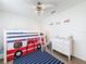 Cozy bedroom with a fun fire truck bunk bed, white dresser, ceiling fan, and blue striped rug at 3344 Gardenia Dr, Hernando Beach, FL 34607