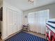 Bedroom with a blue striped rug, white closet doors, window with white curtains, and toddler toys at 3344 Gardenia Dr, Hernando Beach, FL 34607