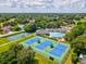 Aerial view of the tennis courts, a community pool, and a playground, all surrounded by lush greenery at 5383 Firethorn Pt, Spring Hill, FL 34609