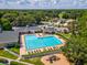 Aerial view of a community pool and playground surrounded by lush trees and residential houses at 5383 Firethorn Pt, Spring Hill, FL 34609