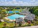 Aerial view of a community pool and tennis courts surrounded by lush greenery and residential houses at 5383 Firethorn Pt, Spring Hill, FL 34609
