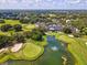 Beautiful aerial view of a golf course with lush green fairways, a pond with a fountain, and a clubhouse at 5383 Firethorn Pt, Spring Hill, FL 34609