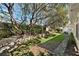 Wide shot of lush backyard featuring a stone retaining wall, mature trees, and a well-manicured lawn at 5383 Firethorn Pt, Spring Hill, FL 34609