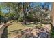 Spacious backyard featuring a stone retaining wall, mature trees, and a lush lawn at 5383 Firethorn Pt, Spring Hill, FL 34609