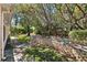 Lush backyard featuring a stone retaining wall, mature trees, and a well-maintained lawn at 5383 Firethorn Pt, Spring Hill, FL 34609