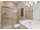 Bathroom featuring walk-in shower with glass door and handrails, white vanity, and neutral tile at 5383 Firethorn Pt, Spring Hill, FL 34609