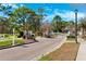 View of the community entrance showcasing brick-paved road, manicured lawns, white fences, and mature trees at 5383 Firethorn Pt, Spring Hill, FL 34609