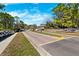 Scenic view of the neighborhood entrance featuring white fencing and a brick-paved road surrounded by lush landscaping at 5383 Firethorn Pt, Spring Hill, FL 34609