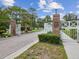Welcoming entrance to the community featuring brick columns, white gates, and well-manicured landscaping at 5383 Firethorn Pt, Spring Hill, FL 34609