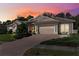 Beautiful home with a brick-paved driveway, manicured lawn, and a two-car garage during sunset at 5383 Firethorn Pt, Spring Hill, FL 34609