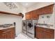 Laundry room features cherry wood cabinets, a granite counter, a sink, and stainless steel washer and dryer at 5383 Firethorn Pt, Spring Hill, FL 34609