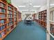 Library with floor to ceiling wood shelving, a table with chairs, and ceiling fans at 5383 Firethorn Pt, Spring Hill, FL 34609