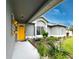 Charming home entrance with vibrant yellow door, lush landscaping, and updated exterior at 5801 65Th N Ter, Pinellas Park, FL 33781