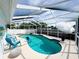 Inviting screened-in pool area featuring a unique kidney-shaped pool, patio furniture, and shade umbrella at 5801 65Th N Ter, Pinellas Park, FL 33781