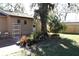 View of the backyard with brick-paved patio, mature trees, plants and a storage shed at 6825 Main St, New Port Richey, FL 34653