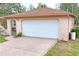A clean, white garage door framed by tan trim, complemented by manicured landscaping at 8159 Alhambra Ct, Spring Hill, FL 34606