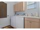 Bright laundry room featuring a white washer and dryer, sink and cabinet with neutral tones and plenty of storage space at 8910 Jericho Rd, Weeki Wachee, FL 34613