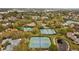 A lovely aerial view of a community pool and tennis courts, surrounded by mature trees and manicured lawns at 1002 Caravel Ct, Tarpon Springs, FL 34689