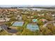 Scenic aerial view of community amenities including swimming pool and tennis courts amid lush landscaping and lakes at 1002 Caravel Ct, Tarpon Springs, FL 34689