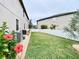 Backyard featuring a well-maintained lawn, white fence, rock border and blooming flowers with two HVAC units at 11611 Lake Blvd, New Port Richey, FL 34655