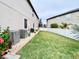 Backyard featuring a well-maintained lawn, white fence, rock border and blooming flowers with two HVAC units at 11611 Lake Blvd, New Port Richey, FL 34655