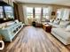 Bright living room featuring wood-look flooring, a comfortable sectional, and large windows at 11611 Lake Blvd, New Port Richey, FL 34655