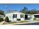 Charming mobile home featuring white siding, black shutters, and a beautifully landscaped front yard at 11641 Quincy Dr # 141, New Port Richey, FL 34654