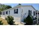 Side view of a white mobile home featuring black shutters and manicured landscaping at 11641 Quincy Dr # 141, New Port Richey, FL 34654