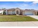 Charming single-story home with manicured lawn, arched entryway, and an attached two-car garage at 14356 Bronte Ct, Hudson, FL 34667