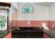 View of the bathtub, pink tiling and stained-glass window in the vintage bathroom at 14448 Linden Dr, Spring Hill, FL 34609