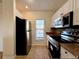 Kitchen with a stainless steel oven, black refrigerator, granite countertops, and tiled floor, creating a modern space at 19325 Water Oak Dr # 205, Port Charlotte, FL 33948