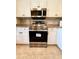 A stainless steel oven and microwave surrounded by white cabinets and granite countertops create a sleek kitchen design at 19325 Water Oak Dr # 205, Port Charlotte, FL 33948