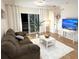 Living room includes two couches, white rug and table, a mounted TV, and access to the balcony at 19325 Water Oak Dr # 205, Port Charlotte, FL 33948