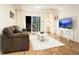 This cozy living room includes two couches, white rug and table, a mounted TV, and balcony access at 19325 Water Oak Dr # 205, Port Charlotte, FL 33948