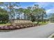 Entrance to The Country Club of the Pines, featuring a brick sign and colorful floral landscaping at 2050 Quailwood Ln, Spring Hill, FL 34606