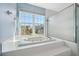 Bright bathroom featuring a garden tub with jets under a large window and a glass door shower at 2764 Countryside Blvd # 3, Clearwater, FL 33761