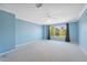 Large living room with wall-to-wall carpet, ceiling fan, and large sunny window at 2764 Countryside Blvd # 3, Clearwater, FL 33761