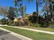 Landscaped single-story home with terracotta roof seen from the sidewalk amid dense foliage and palm trees at 2806 Grey Oaks Blvd, Tarpon Springs, FL 34688