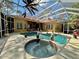 View of a screened pool and spa, surrounded by mature trees and a beautiful outdoor living space at 2806 Grey Oaks Blvd, Tarpon Springs, FL 34688